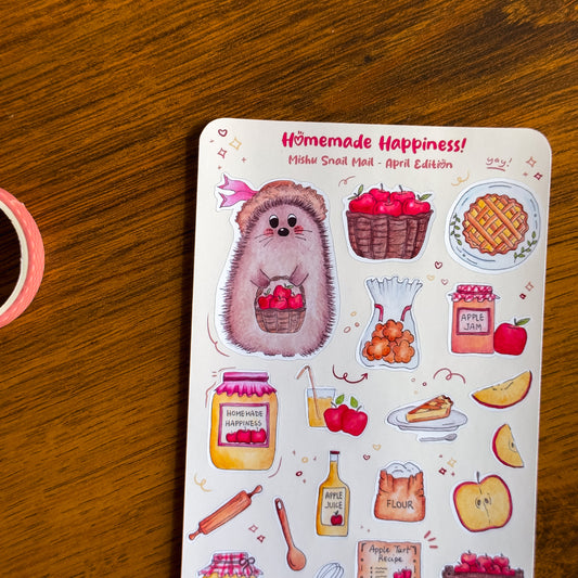 close up of the kawaii sticker sheet from the Mishu Snail Mail April Edition "Homemade Happiness", featuring Mishu the Hedgehog and hand-illustrated apple-themed designs on a wooden surface.