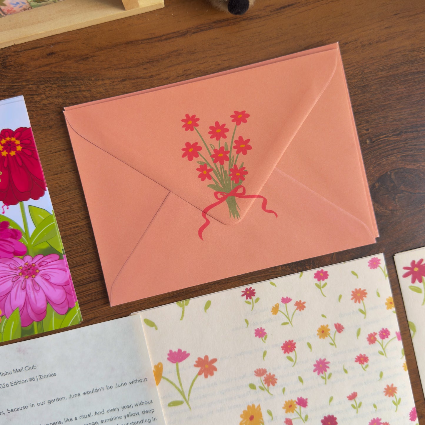 Pink envelope with floral design on a wooden surface