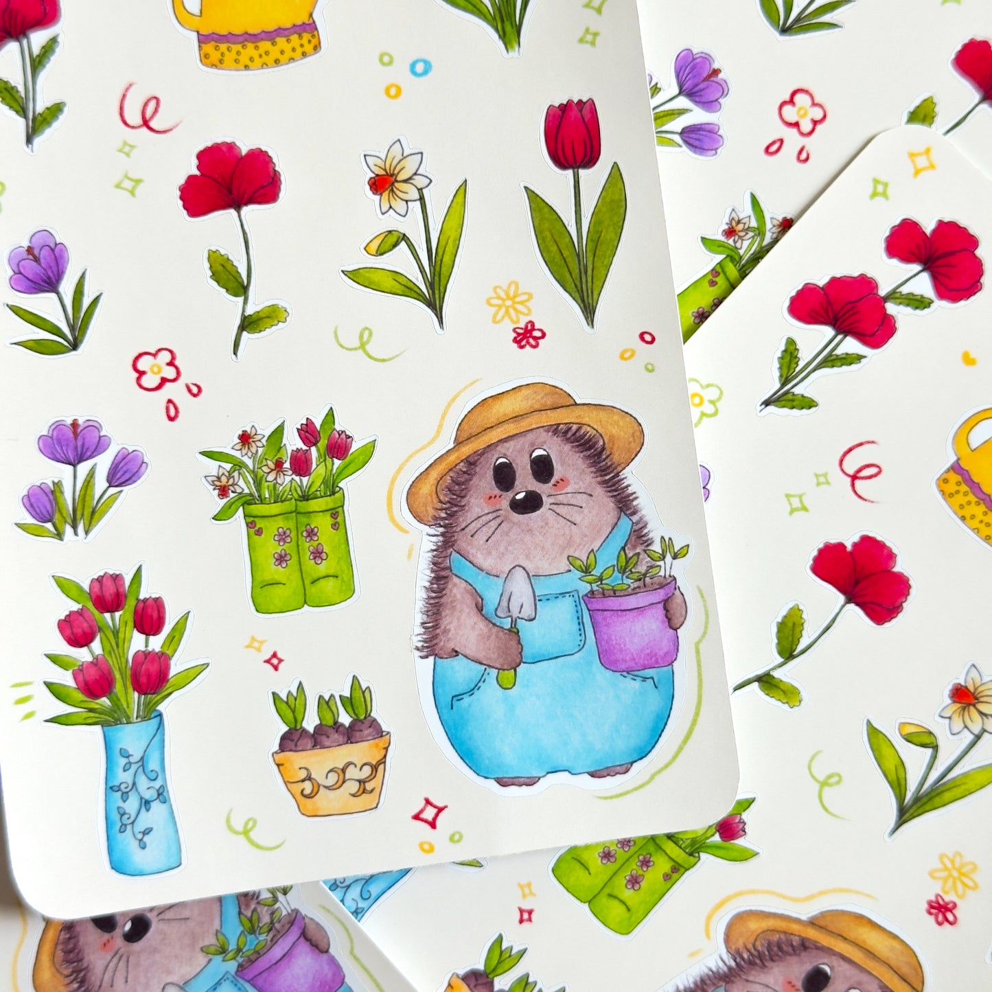 Close up on a sticker sheet featuring a hedgehog gardener with flowers and plants on a white background