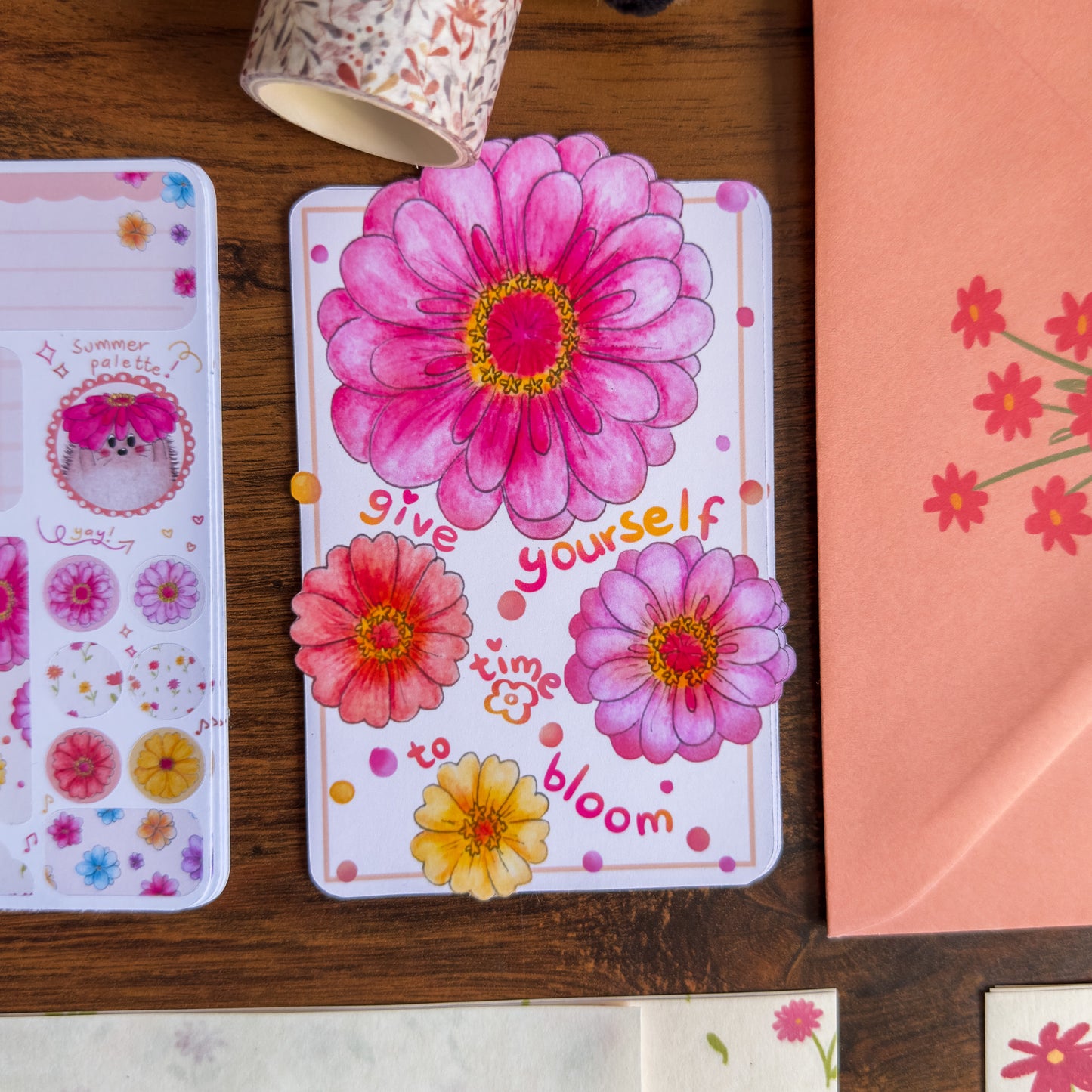 Floral-themed die cut sticker with motivational text on a wooden surface