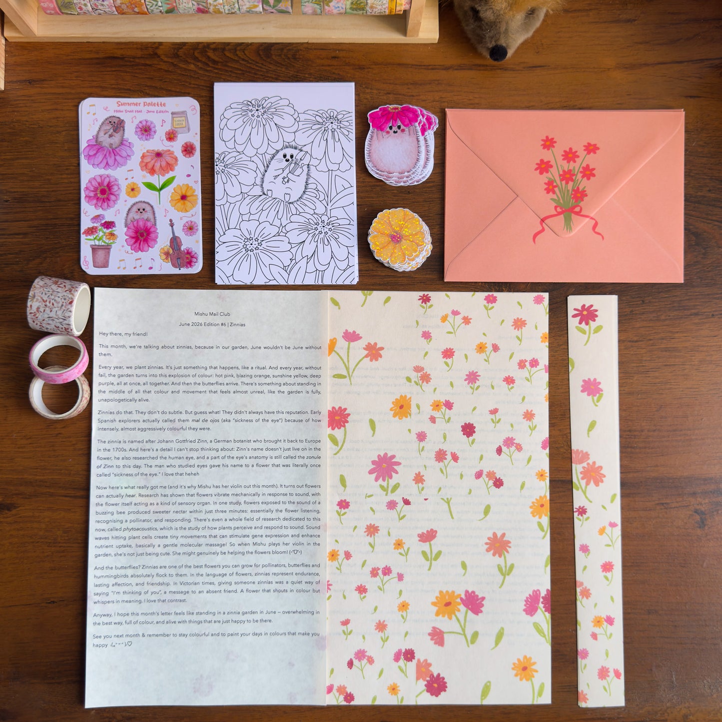 Stationery items including a letter, envelope, stickers, and paper with floral designs on a wooden surface.
