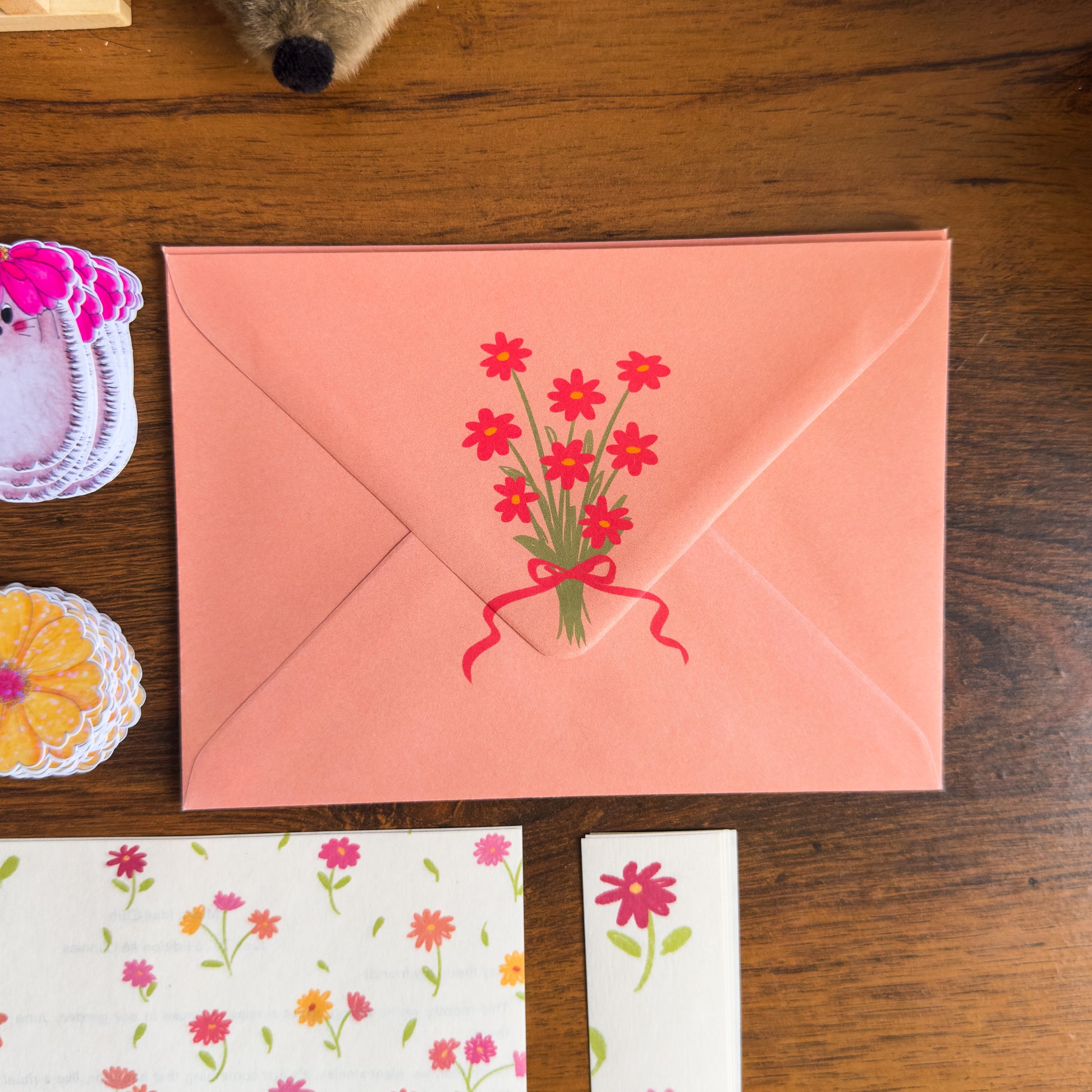 Pink envelope with floral design on a wooden surface