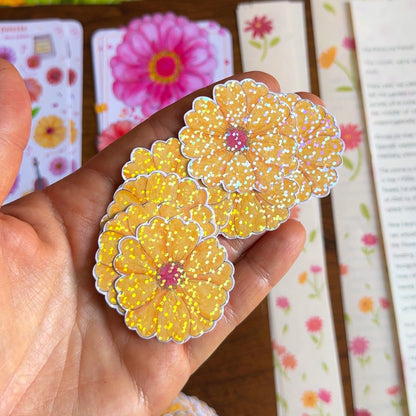 Hand holding laminated yellow floral stickers with a colorful background