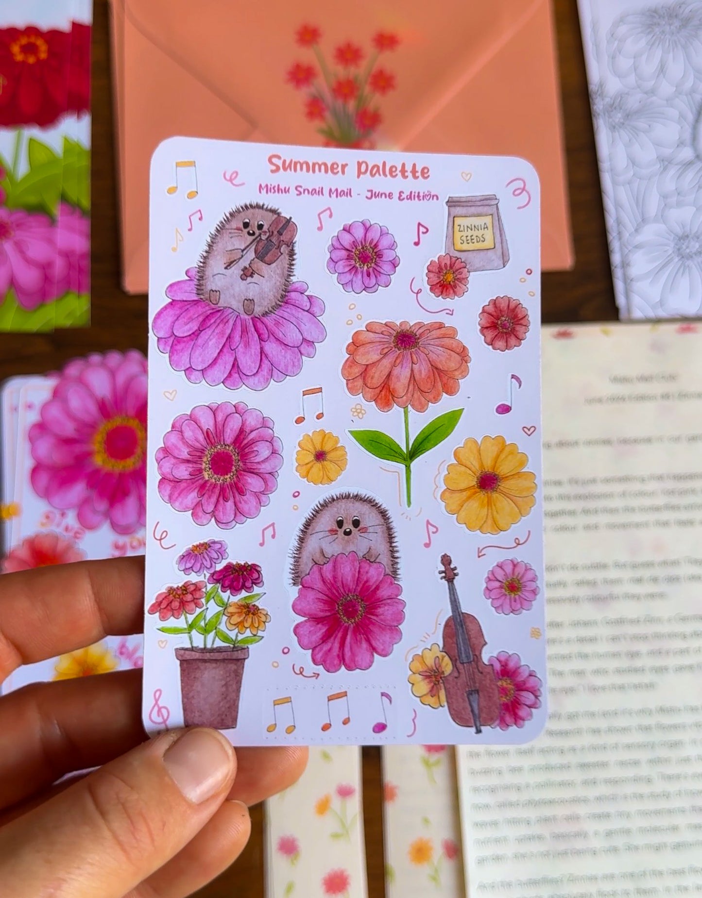 Sticker sheet with hedgehogs and flowers held by a hand against a colorful background.